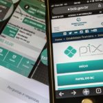 Aparelho celular com o Pix aberto em um fundo com um site de transações financeiras